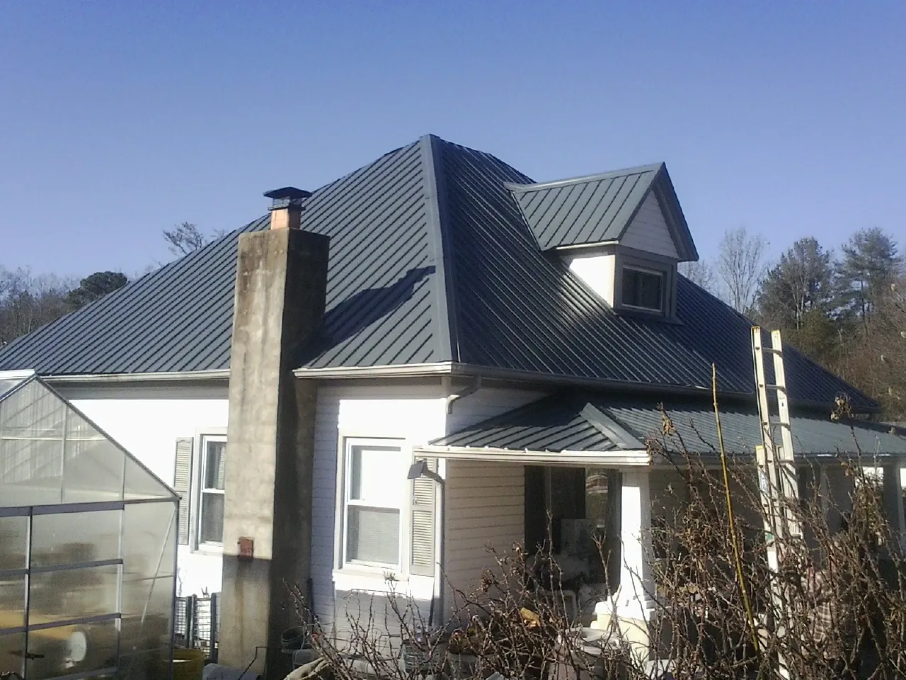 Dark blue standing seam metal roof on a white farmhouse with dormer — Slate & Tile Roof Repair by Roofing Brothers in Newfoundland