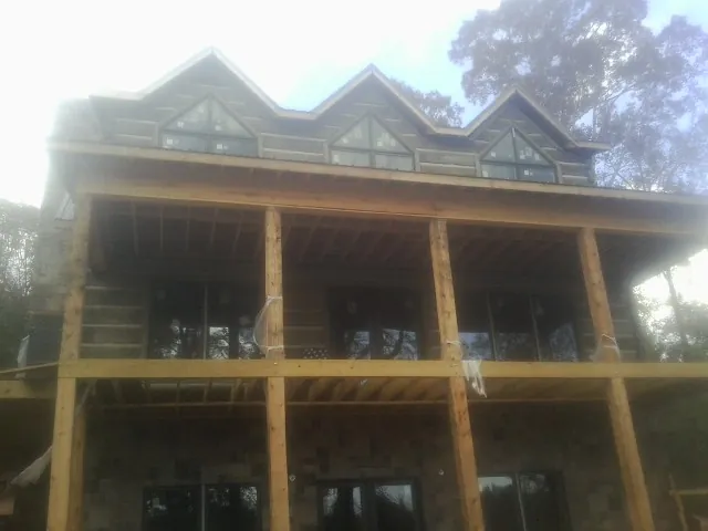 Dormers and porch framing on a large log home under construction — Roof Coating work by our crew in Newfoundland