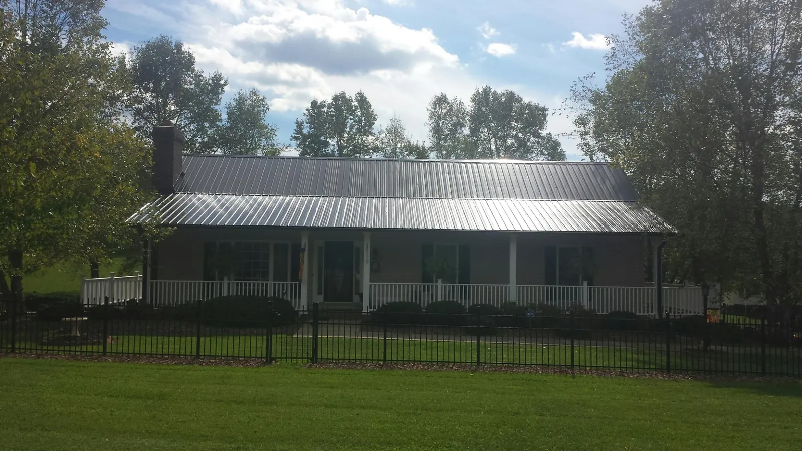 Gray metal roof on a brick ranch with a full width front porch — Gutter Guard Installation work by our crew in Newfoundland