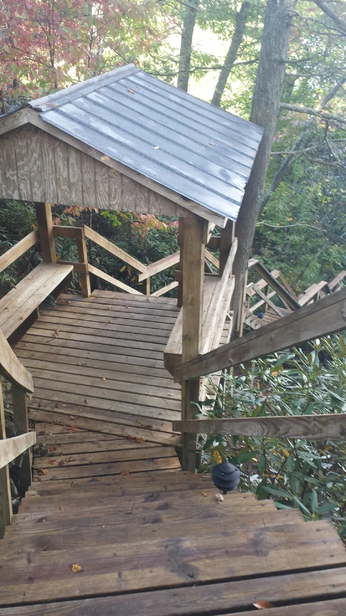 Metal roofed shelter over wooden steps on a wooded walkway — Skylight Repair & Installation work by our crew in Newfoundland