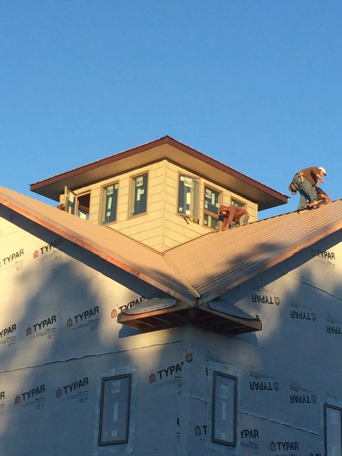 Roofers working around a rooftop cupola on a new metal roof at sunset — Roof Waterproofing in Newfoundland by Roofing Brothers